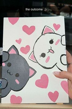 someone is holding up a card with two cats on it and hearts in the background