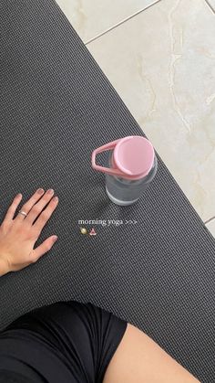 a woman is sitting on the floor with her hand near a coffee cup