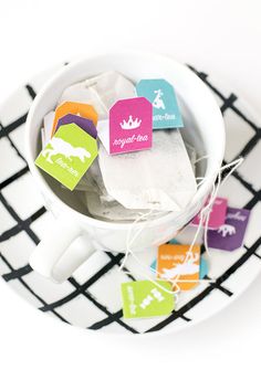 colorful tea bags in a white cup on a black and white plate