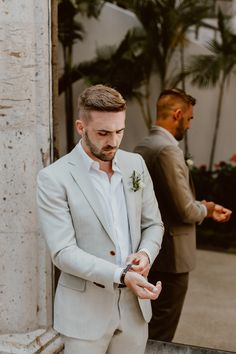 a man in a white suit standing next to another man