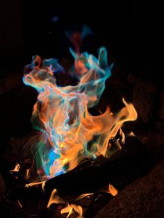 the fire is glowing brightly with blue and yellow flames on it's side,