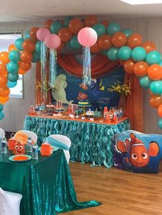 an under the sea themed birthday party with balloons, decorations and table cloths on wood flooring