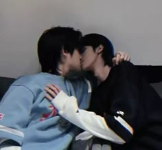 two people kissing each other while sitting on a couch