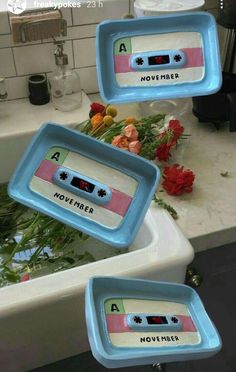 three blue trays sitting on top of a sink filled with flowers