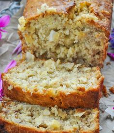 two slices of banana bread sitting on top of a piece of paper next to purple flowers