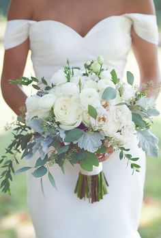 a bride holding a bouquet of white flowers