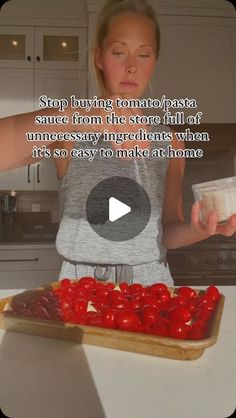 a woman standing in front of a tray filled with tomatoes and ketchup on top of a kitchen counter