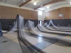 there are many skateboard ramps in the room with nets on them and people standing around