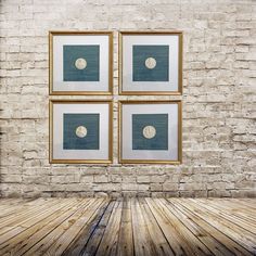 four framed pictures on a brick wall in front of a wooden floor with an empty space between them