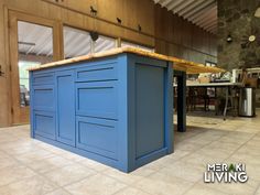 a blue kitchen island in the middle of a room with tile flooring and walls