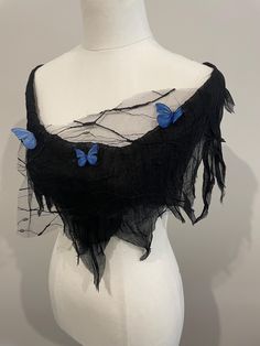 a white mannequin wearing a black shawl with blue butterflies on the top