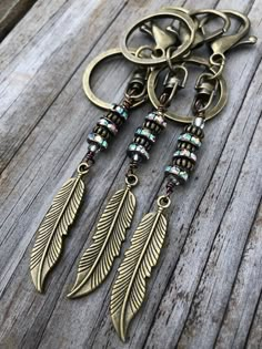 an antique style keychain with feathers hanging from it's side on a wooden surface