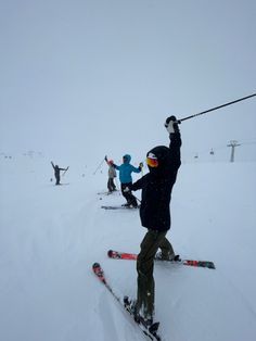 several skiers are skiing down a snowy mountain slope with their ski poles in the air