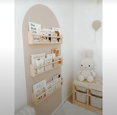 a white teddy bear sitting on top of a shelf next to a wall mounted book case