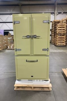 a green refrigerator sitting on top of a wooden pallet in a room filled with boxes