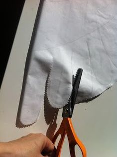 someone is cutting fabric with scissors on a piece of white paper that has been folded