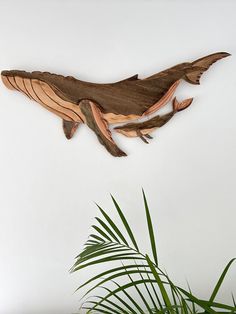 a wooden sculpture of a lizard hanging on the wall next to a potted plant