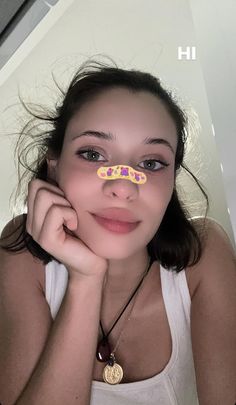 a young woman wearing a white tank top is posing with her hand on her cheek