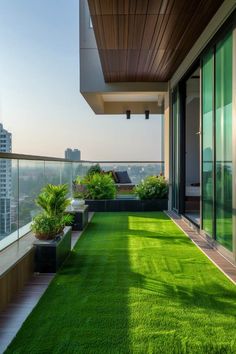 a balcony with grass and potted plants on the roof deck, overlooking cityscape