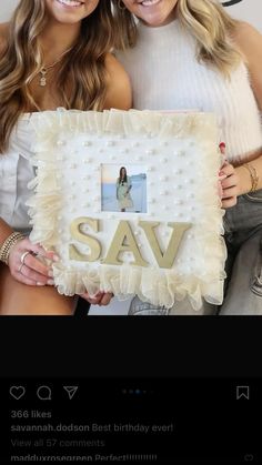 two beautiful young women holding up a white cake with the words sav on it