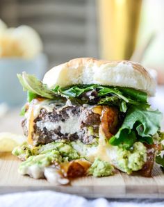 a close up of a sandwich on a cutting board with lettuce and other toppings