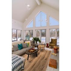 a living room filled with furniture and lots of windows on top of a wooden floor