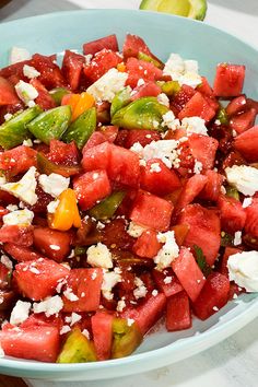 a watermelon salad with feta cheese and green peppers in a blue bowl