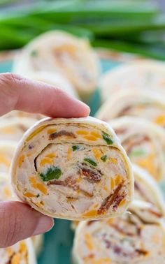 a hand holding up a tortilla with cheese and other food items in the background