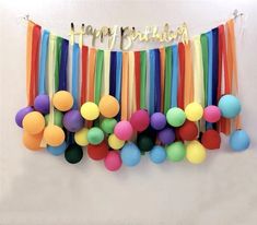 colorful streamers and balloons are hanging on the wall with happy birthday written above them