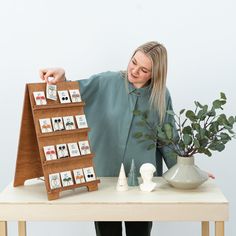 a woman standing next to a wooden table with cards on it and a potted plant