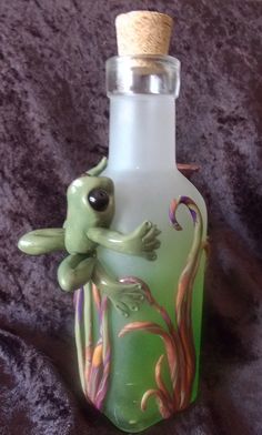 a green glass bottle with a frog on it