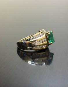 DeKara Designs Classic Handmade Art Deco Oval Emerald and Diamond Ring. Metal- 14K Yellow Gold, .583 Stones- 1 Emerald Cut Colombian Emerald 1.52 Carats, 18 Baguette Diamonds H-I, 16 Round Diamonds G-H Color VS2 Clarity 1.75 Carats. Size- 5 1/2. Free sizing. Art Deco Influenced Beautiful Colombian Emerald Diamond Engagement Ring. There is a beautiful 1.52 carat green emerald in the center of the ring that is emerald cut and expertly prong set. There are baguettes that are channel set on the side Art Deco Yellow Gold Emerald Ring With Brilliant Cut, Yellow Gold Wedding Ring With 17 Jewels, Gold Emerald Diamond Ring With Baguette Cut, Classic Gold Emerald Wedding Ring, Fine Jewelry Gold Emerald Ring Baguette Cut, 14k Stamped Baguette Cut Fine Jewelry, Fine Jewelry With Stamped 14k Baguette Cut, Fine Jewelry Stamped 14k With Baguette Cut, Wedding Cluster Ring Emerald Cut Stamped 14k