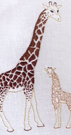 two giraffes standing next to each other on a white cloth with gold trim