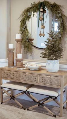 a table with two benches and a mirror on the wall in front of it that is decorated with greenery