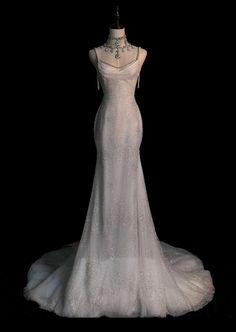 a white wedding dress on display in front of a black background with the back of it's neckline