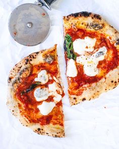 two slices of pizza sitting on top of a white paper covered table next to a grater