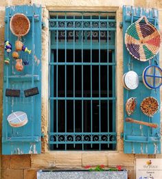 an old window with blue shutters and decorative items on it