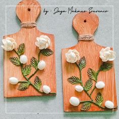 two wooden cutting boards with flowers and leaves on them, one is made out of wood