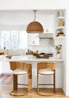 two wicker stools sit in front of an island with white marble countertops