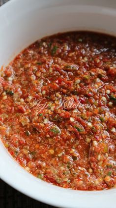 a white bowl filled with red sauce and garnished with green peppers on top