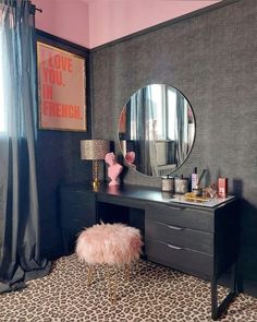 a vanity table with a mirror and stool in a room that has leopard print on the floor