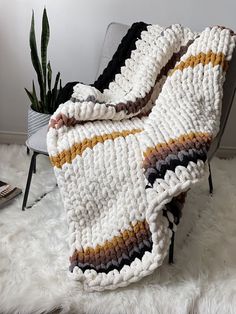 a crocheted blanket sitting on top of a chair next to a potted plant