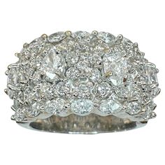 a white gold ring with diamonds on the sides and an oval center surrounded by smaller round stones