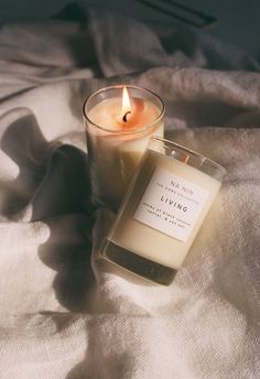 a candle sitting on top of a bed next to a white blanket