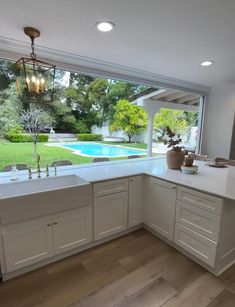 a kitchen with a large window overlooking the backyard and pool in the backround