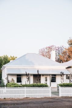 a white house with a picket fence and trees in the background