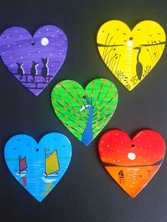 four heart shaped magnets on a black surface with one painted like a sailboat