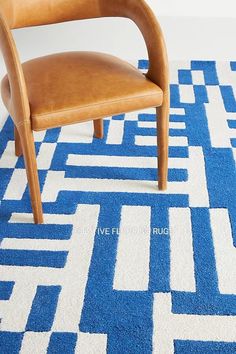 a brown chair sitting on top of a blue and white rug next to a wooden chair