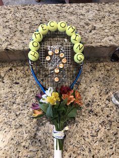 a tennis racquet decorated with balls and flowers sits on a granite counter top