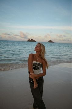 a woman standing on top of a beach next to the ocean